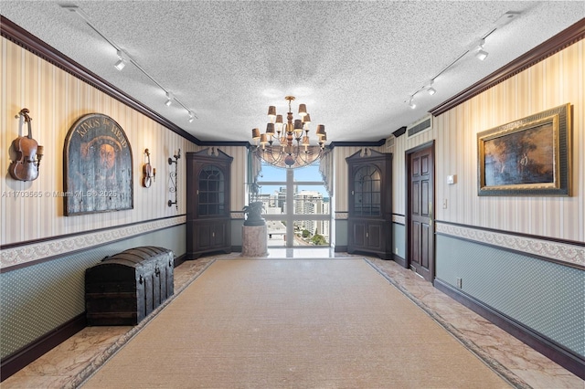 5500 Collins Ave Unit 2302, Miami Beach, FL 33140 - unfurnished dining area with track lighting, ornamental molding, wallpapered walls, a chandelier, and a textured ceiling