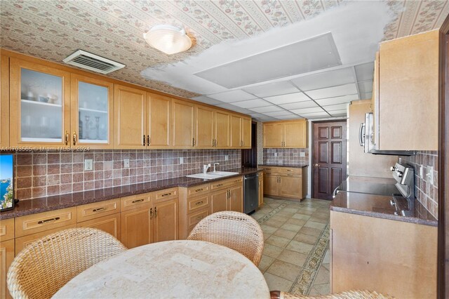 kitchen with sink, black dishwasher, backsplash, dark stone counters, and stainless steel range with electric stovetop