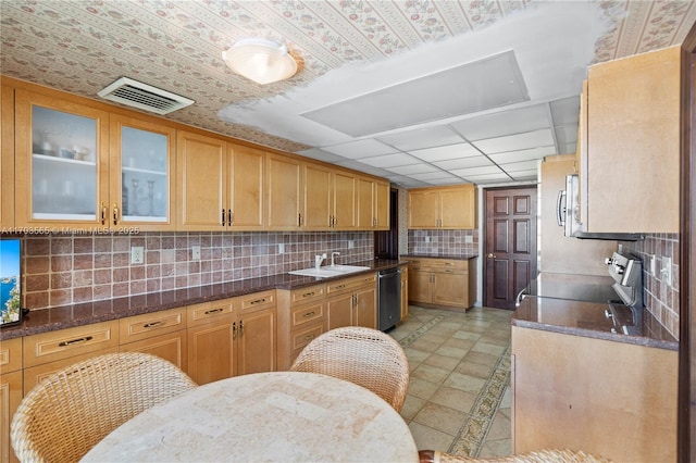 5500 Collins Ave Unit 2302, Miami Beach, FL 33140 - kitchen with stove, dishwasher, tasteful backsplash, glass insert cabinets, and dark stone counters