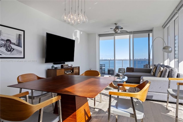 living room featuring expansive windows, ceiling fan with notable chandelier, and hardwood / wood-style flooring