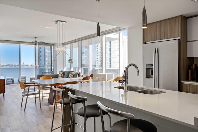 kitchen with stainless steel fridge with ice dispenser, sink, a water view, and decorative light fixtures