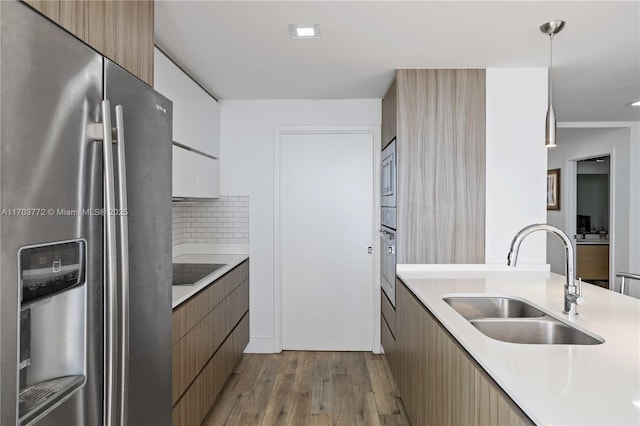 kitchen featuring decorative backsplash, stainless steel refrigerator with ice dispenser, sink, decorative light fixtures, and light hardwood / wood-style floors