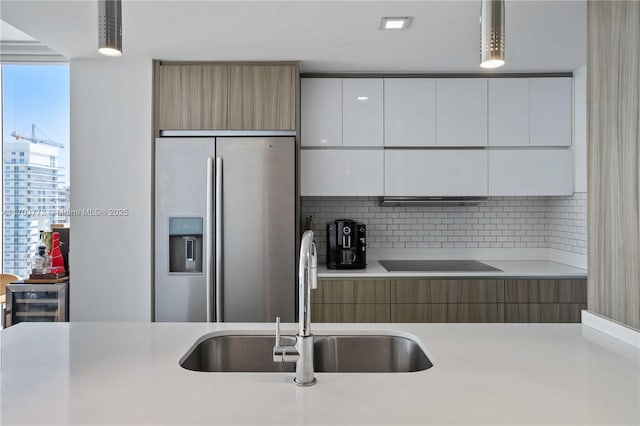 kitchen with white cabinetry, sink, hanging light fixtures, stainless steel fridge with ice dispenser, and black electric stovetop