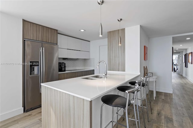 kitchen featuring white cabinets, sink, hanging light fixtures, built in refrigerator, and tasteful backsplash