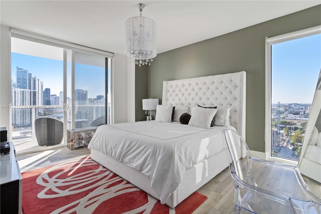 bedroom featuring expansive windows, light hardwood / wood-style floors, and a chandelier