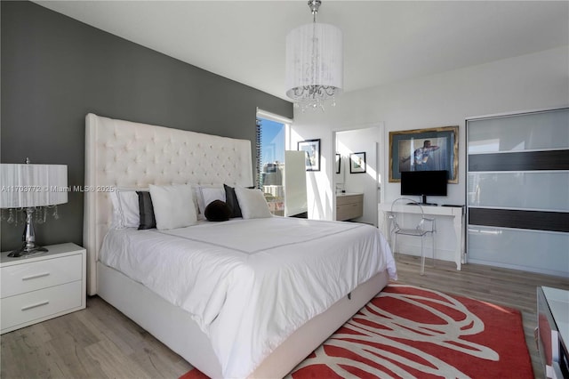 bedroom with light hardwood / wood-style flooring and a chandelier