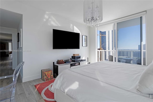 bedroom with floor to ceiling windows, hardwood / wood-style floors, and a notable chandelier