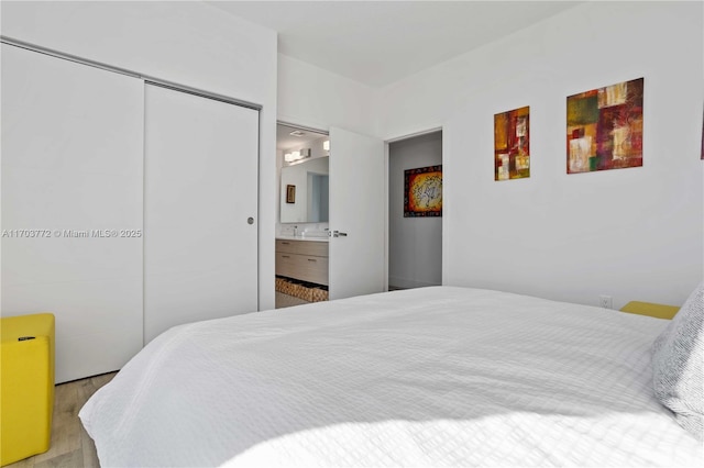 bedroom with connected bathroom, a closet, and light hardwood / wood-style floors