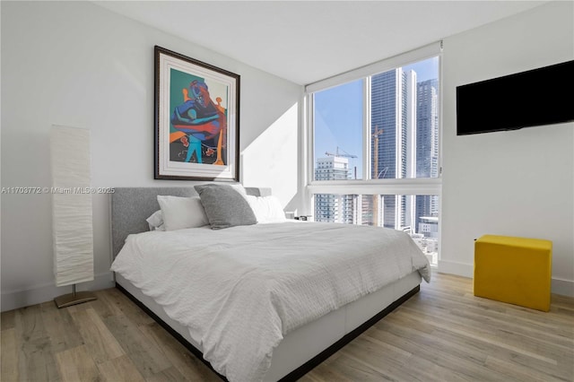 bedroom with expansive windows and light wood-type flooring