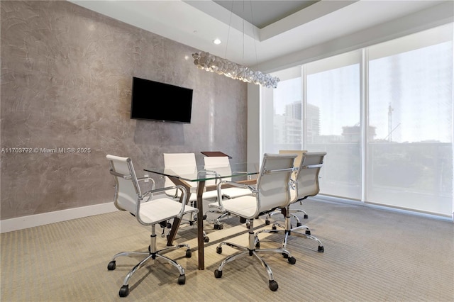 carpeted dining space with a tray ceiling