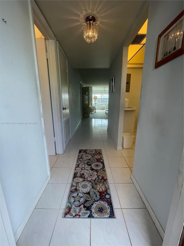 hall featuring light tile patterned flooring and a notable chandelier