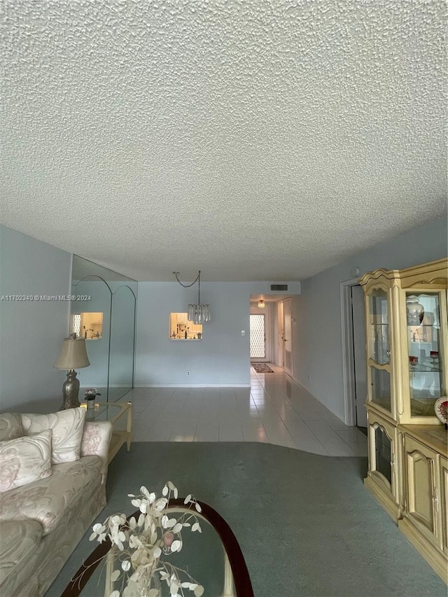 living room with a chandelier, a textured ceiling, and tile patterned floors