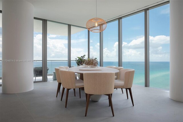 dining space featuring expansive windows, a healthy amount of sunlight, a water view, and a chandelier