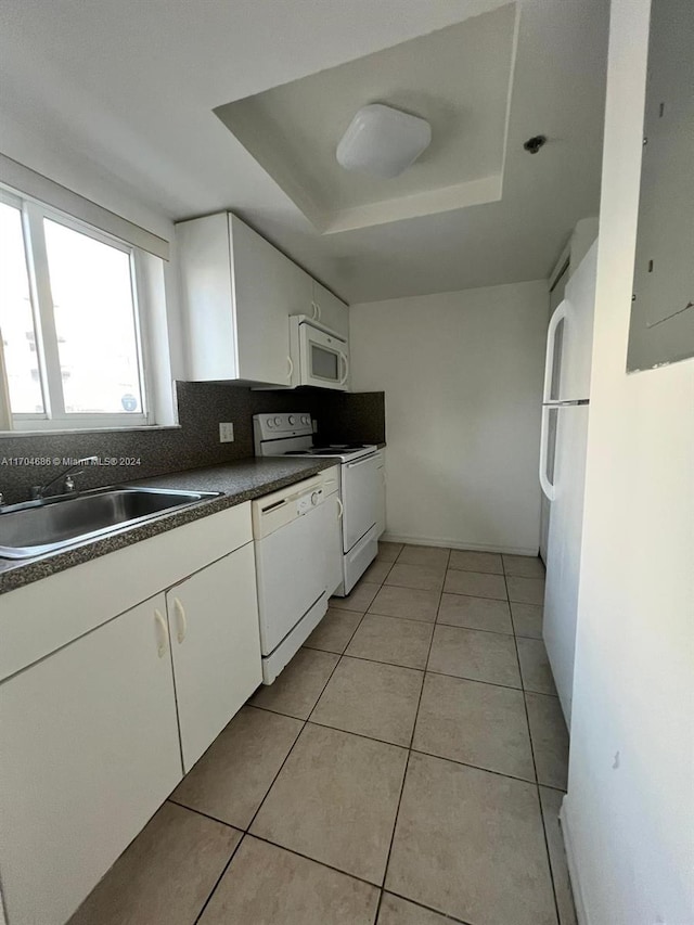 kitchen with sink, white appliances, a tray ceiling, decorative backsplash, and white cabinets