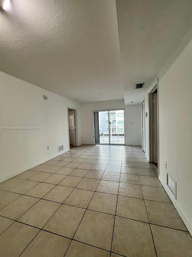 empty room with light tile patterned floors and a textured ceiling