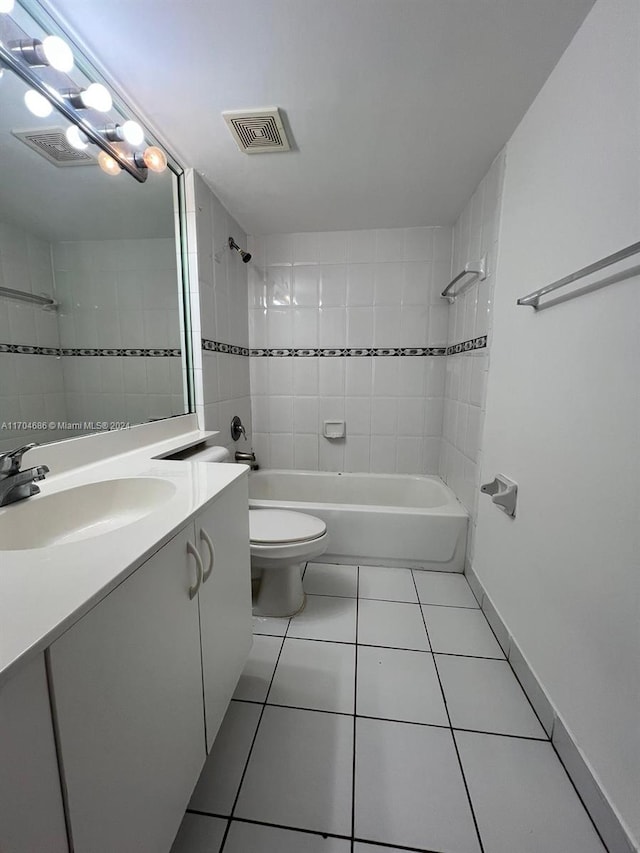 full bathroom with tile patterned floors, vanity, tiled shower / bath combo, and toilet