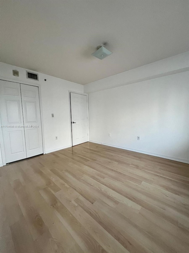 unfurnished bedroom featuring light hardwood / wood-style flooring and a closet