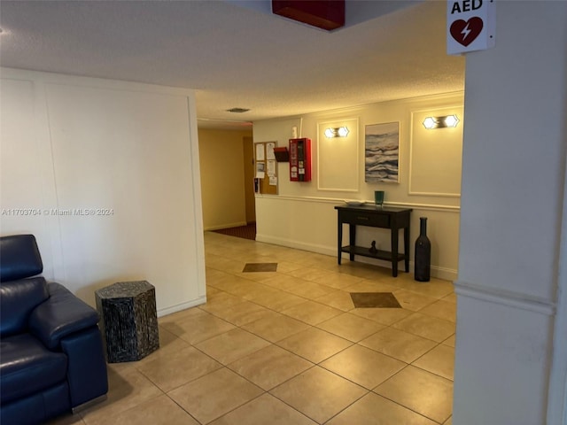 hall with light tile patterned floors and a textured ceiling