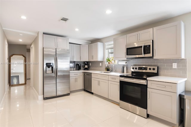 kitchen featuring appliances with stainless steel finishes, tasteful backsplash, light tile patterned floors, and sink