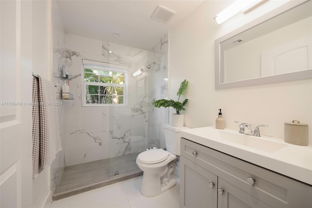 bathroom with tile patterned floors, vanity, tiled shower, and toilet