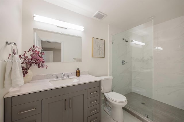 bathroom featuring tile patterned floors, toilet, vanity, and tiled shower