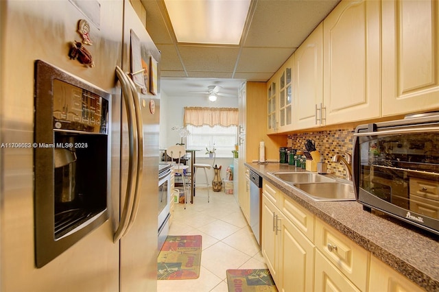 kitchen with a drop ceiling, backsplash, sink, light tile patterned floors, and stainless steel appliances