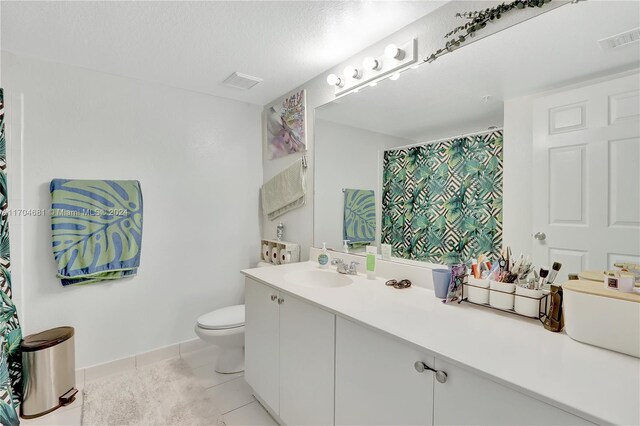 bathroom featuring tile patterned floors, vanity, a textured ceiling, and toilet