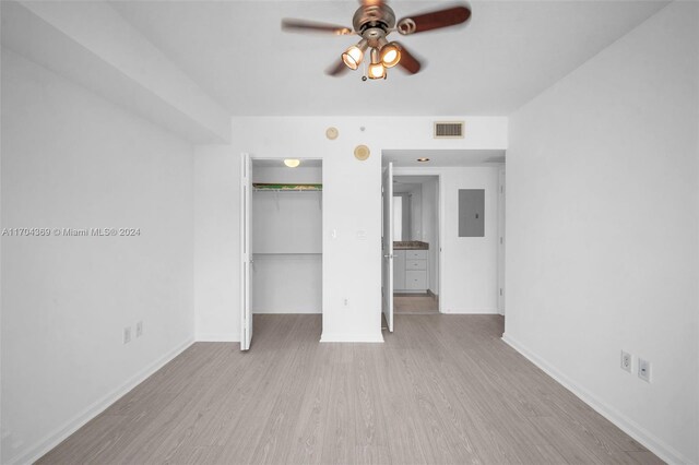 unfurnished bedroom featuring a closet, electric panel, light hardwood / wood-style floors, and ceiling fan