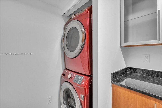 laundry room with cabinets and stacked washer / dryer