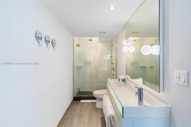 bathroom featuring hardwood / wood-style floors, vanity, a shower with shower door, and toilet