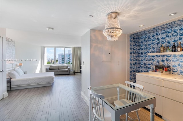 bedroom featuring electric panel, a chandelier, and wood-type flooring