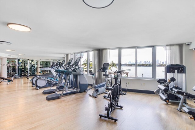 gym featuring hardwood / wood-style floors and a water view