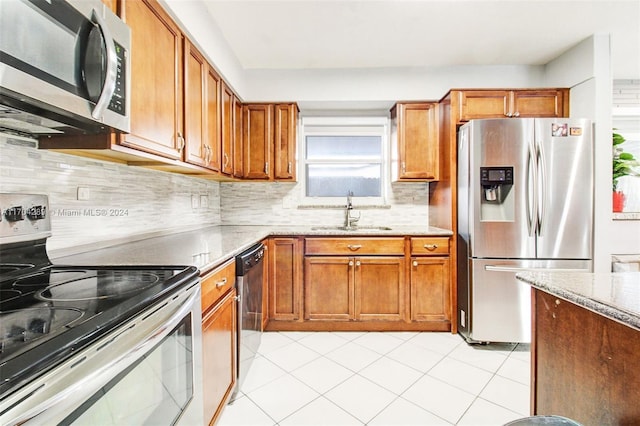 kitchen with light stone countertops, sink, stainless steel appliances, decorative backsplash, and light tile patterned floors