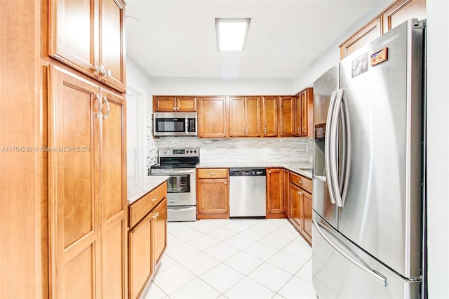 kitchen featuring decorative backsplash, light tile patterned floors, stainless steel appliances, and light stone counters