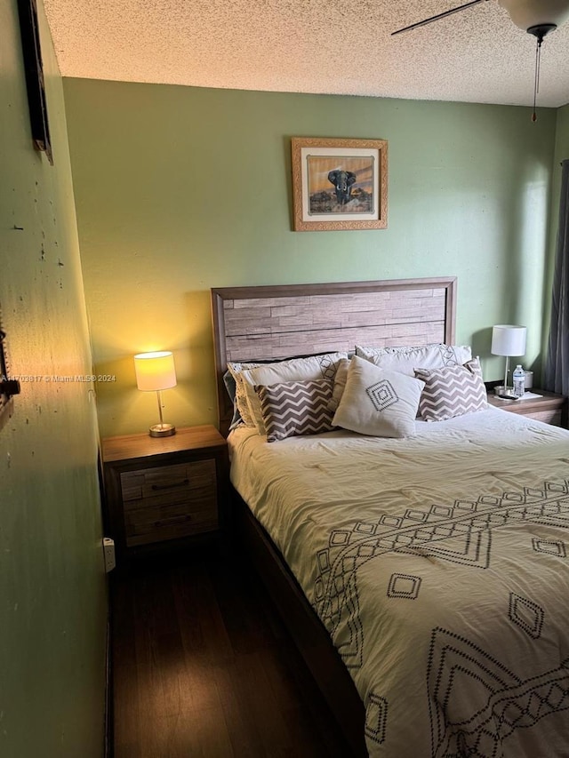 bedroom featuring ceiling fan, dark wood-type flooring, and a textured ceiling