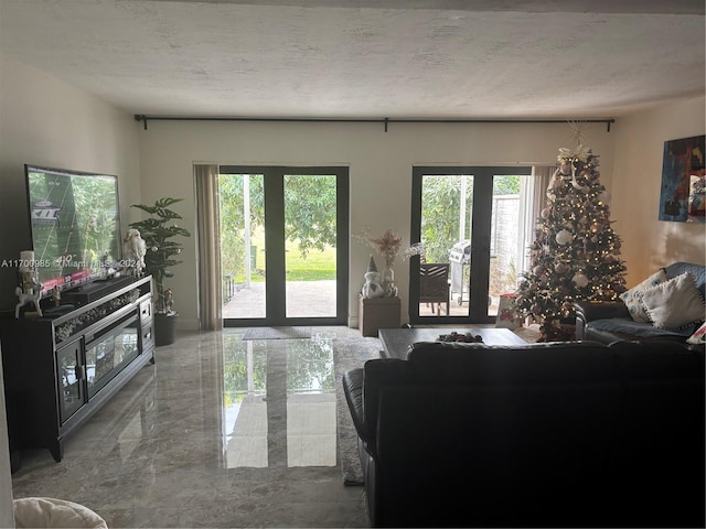 living room with a healthy amount of sunlight, a textured ceiling, and french doors