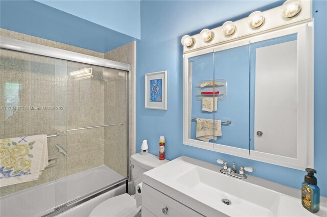 full bathroom with shower / bath combination with glass door, vanity, and toilet