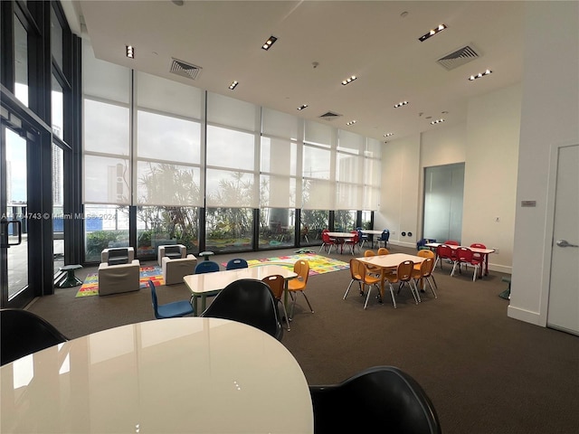 dining space featuring carpet flooring, floor to ceiling windows, and a towering ceiling