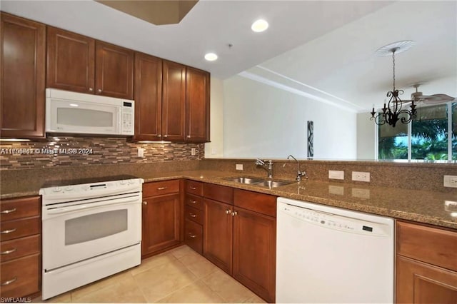 kitchen featuring backsplash, white appliances, sink, a notable chandelier, and dark stone countertops