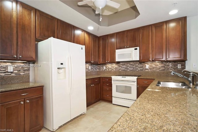 kitchen with decorative backsplash, white appliances, light stone counters, and sink