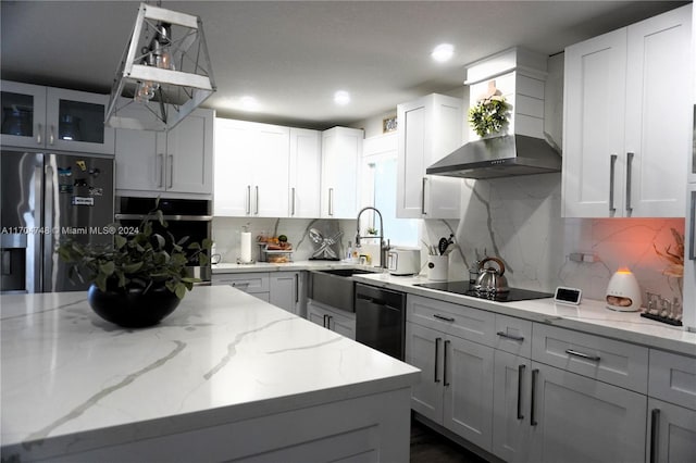 kitchen with wall chimney exhaust hood, tasteful backsplash, light stone counters, white cabinets, and black appliances