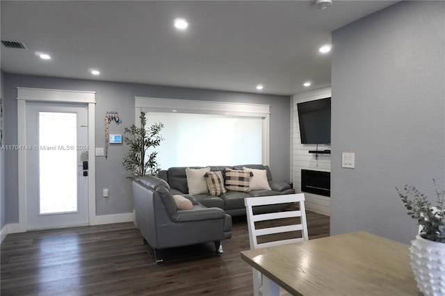 living room featuring dark hardwood / wood-style flooring and a large fireplace