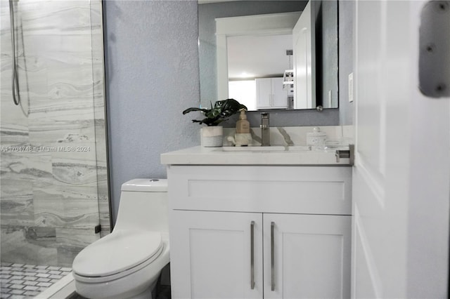 bathroom with tiled shower, vanity, and toilet