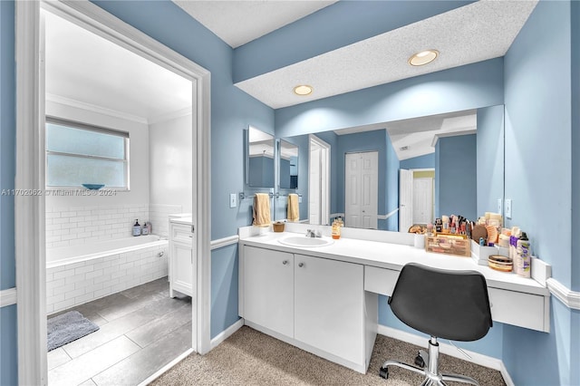 bathroom featuring tiled bath, vanity, and a textured ceiling