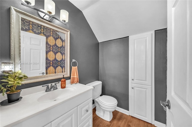 bathroom featuring toilet, wood-type flooring, vanity, and vaulted ceiling