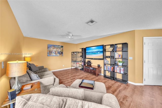 living room featuring wood-type flooring, a textured ceiling, and ceiling fan