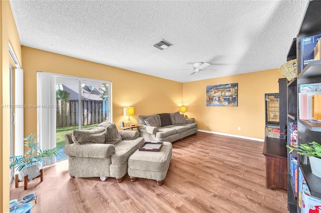 living room featuring hardwood / wood-style flooring, ceiling fan, and a textured ceiling