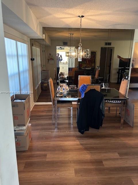 dining space with a chandelier, a textured ceiling, and hardwood / wood-style flooring