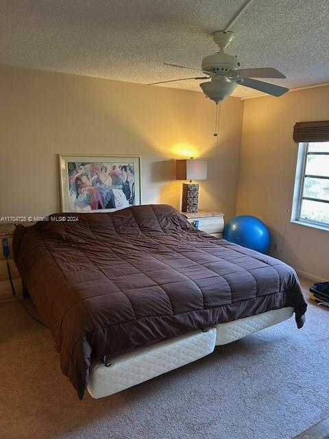 bedroom with carpet, ceiling fan, and a textured ceiling