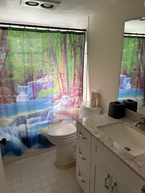 full bathroom with toilet, tile patterned floors, vanity, and shower / tub combo with curtain